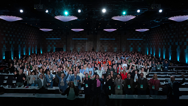 Mange mennesker i en stor sal som ser mot kamera