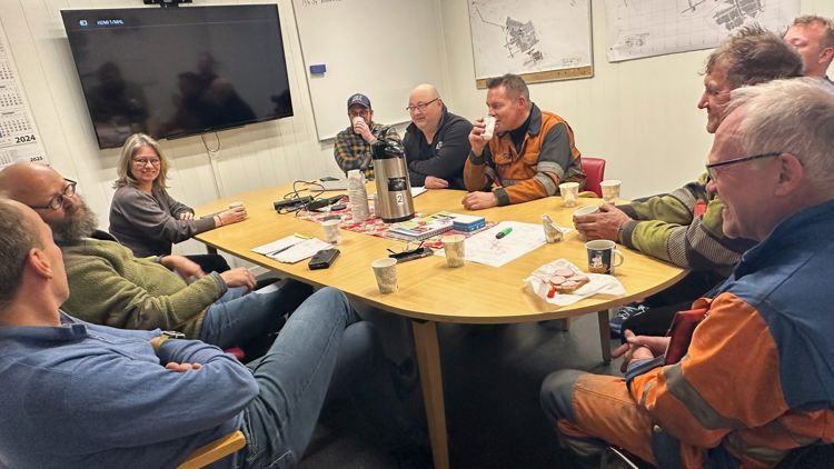 Inspektører fra arbeidstilsynet sitter rundt et bord og prater med seks ansatte i gruveselskapet